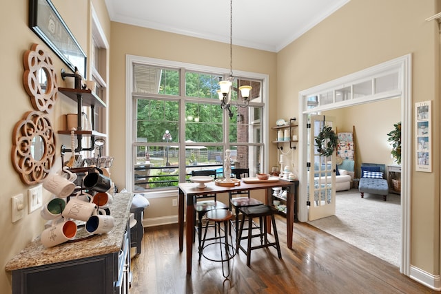 dining space featuring dark wood-type flooring, crown molding, and a notable chandelier