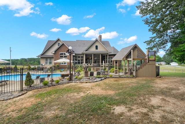 back of property with a fenced in pool