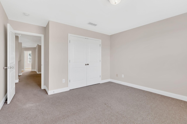 unfurnished bedroom featuring light colored carpet and a closet