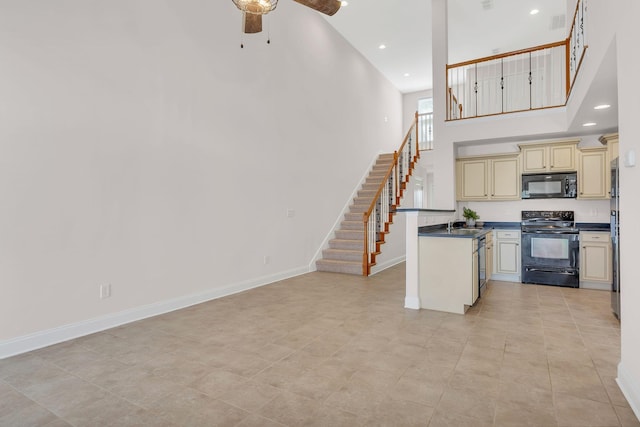 kitchen featuring sink, a high ceiling, ceiling fan, black appliances, and cream cabinetry