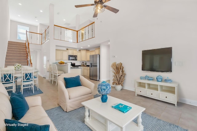 living room with a high ceiling, light tile patterned floors, and ceiling fan