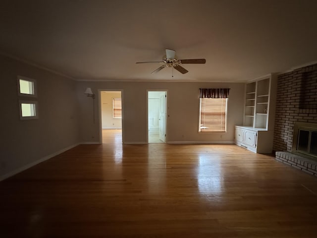 unfurnished living room featuring ceiling fan, a fireplace, wood-type flooring, and plenty of natural light