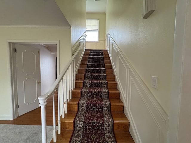 stairs with hardwood / wood-style floors and crown molding