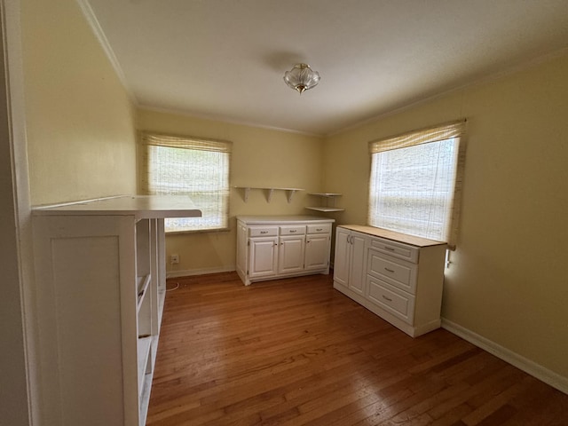 kitchen featuring kitchen peninsula, white cabinetry, ornamental molding, and light hardwood / wood-style flooring