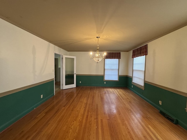 unfurnished dining area featuring hardwood / wood-style floors and a notable chandelier