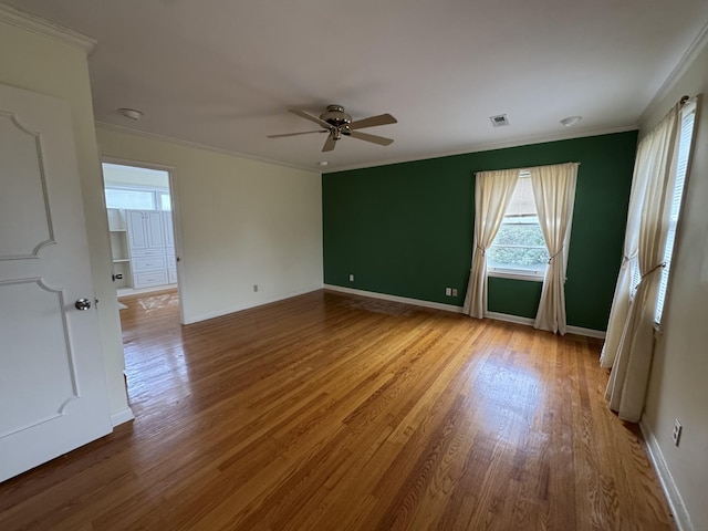 unfurnished room with hardwood / wood-style floors, ceiling fan, and crown molding