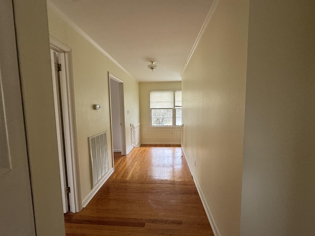 corridor with light hardwood / wood-style floors and ornamental molding