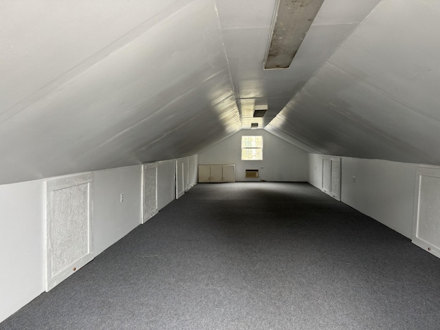 additional living space featuring vaulted ceiling and dark colored carpet