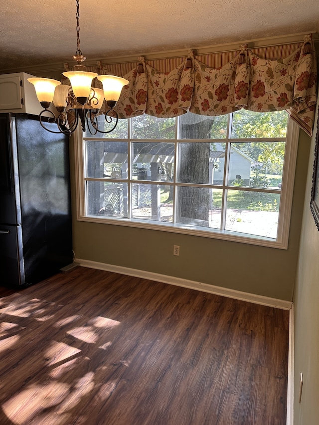 unfurnished dining area featuring dark hardwood / wood-style floors, a notable chandelier, and a textured ceiling