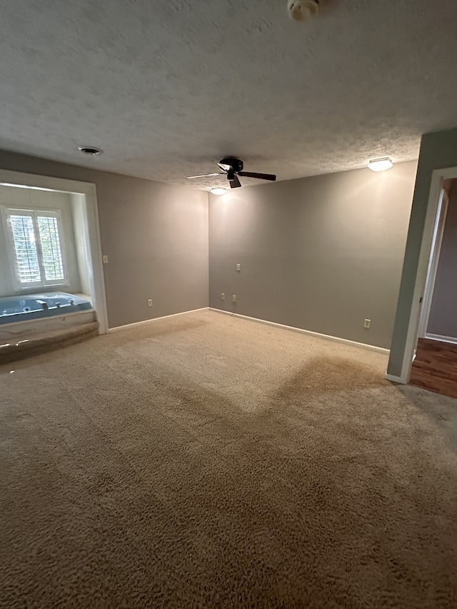 carpeted spare room with ceiling fan and a textured ceiling