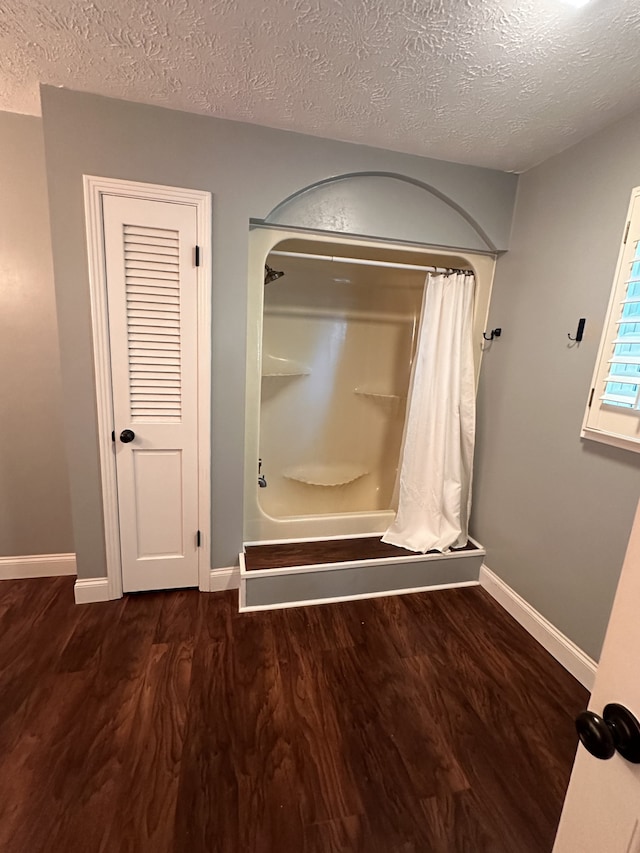 bathroom with shower / bath combination with curtain, hardwood / wood-style floors, and a textured ceiling