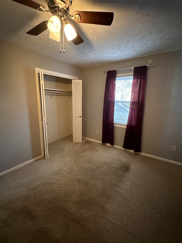 unfurnished bedroom with ceiling fan, a textured ceiling, a closet, and carpet flooring