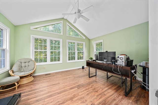 office space featuring vaulted ceiling, plenty of natural light, ceiling fan, and light wood-type flooring