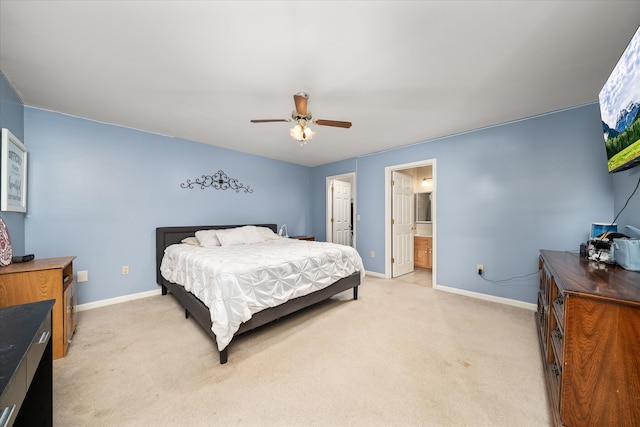 bedroom featuring ensuite bathroom, light colored carpet, and ceiling fan