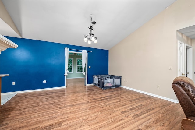 living room with an inviting chandelier, hardwood / wood-style flooring, and lofted ceiling