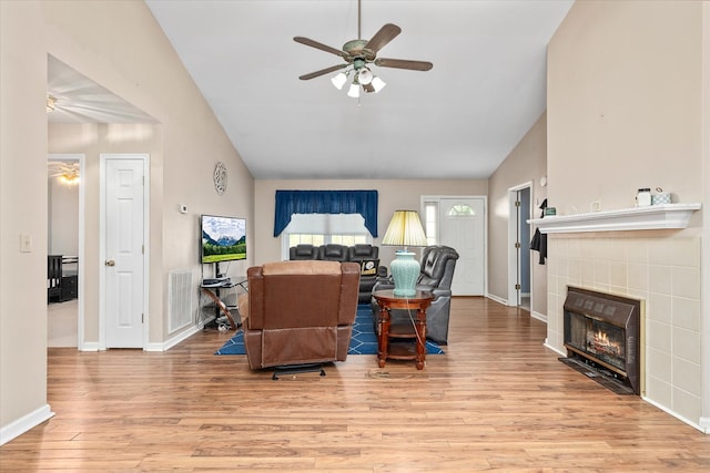 living room featuring vaulted ceiling, ceiling fan, a fireplace, and light hardwood / wood-style floors