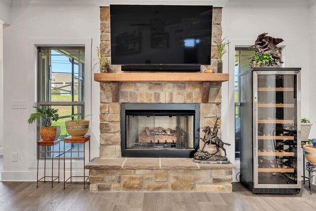 interior details featuring a fireplace, wood-type flooring, ornamental molding, and beverage cooler