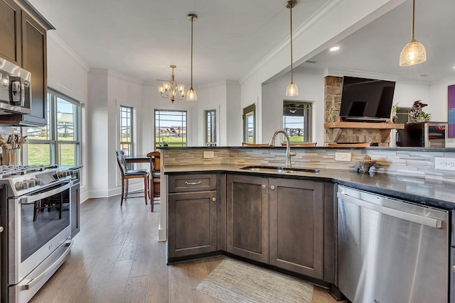 kitchen featuring pendant lighting, sink, appliances with stainless steel finishes, dark brown cabinetry, and decorative backsplash