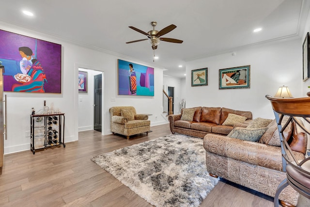 living room featuring ceiling fan, ornamental molding, and light wood-type flooring