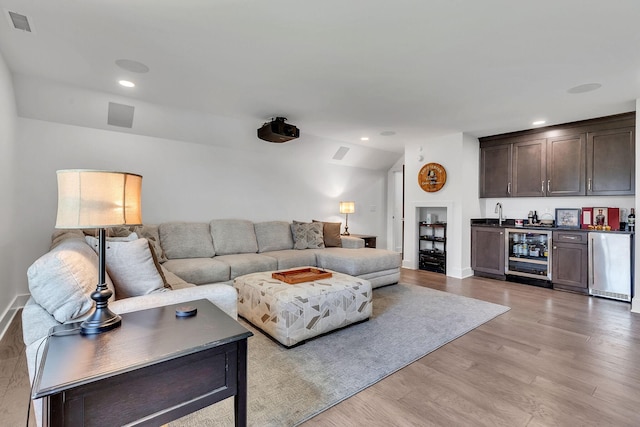 living room featuring wine cooler, bar, and light wood-type flooring