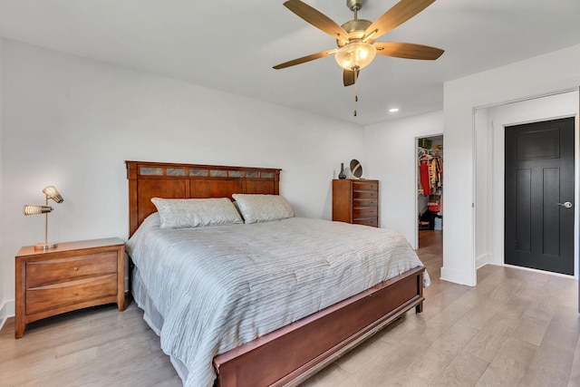 bedroom with ceiling fan, a walk in closet, a closet, and light wood-type flooring