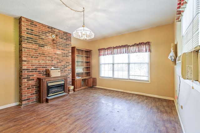 unfurnished living room with dark hardwood / wood-style floors, brick wall, a chandelier, and a textured ceiling