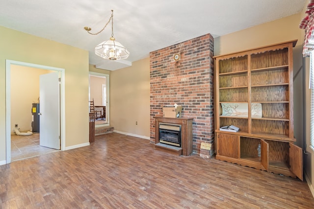 unfurnished living room featuring brick wall, a notable chandelier, and hardwood / wood-style flooring