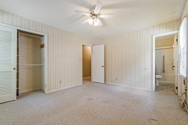 unfurnished bedroom featuring light tile patterned flooring, ceiling fan, a closet, and connected bathroom