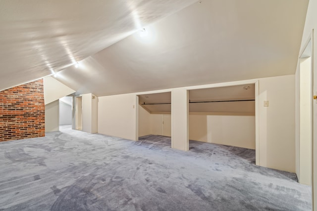 additional living space with lofted ceiling, carpet flooring, and brick wall