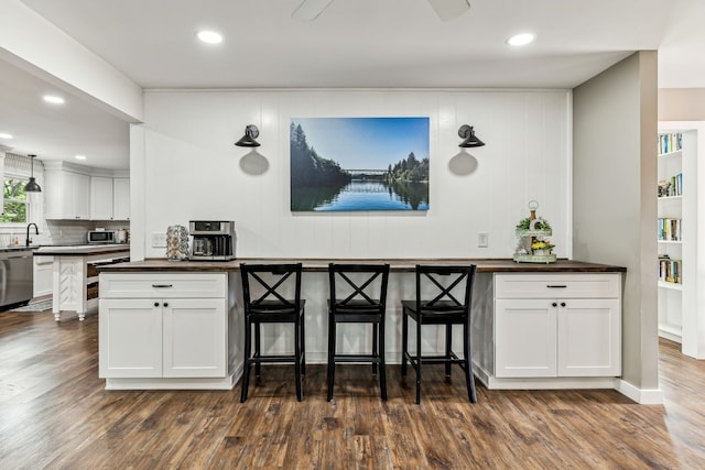 kitchen with tasteful backsplash, stainless steel appliances, sink, white cabinetry, and dark hardwood / wood-style flooring