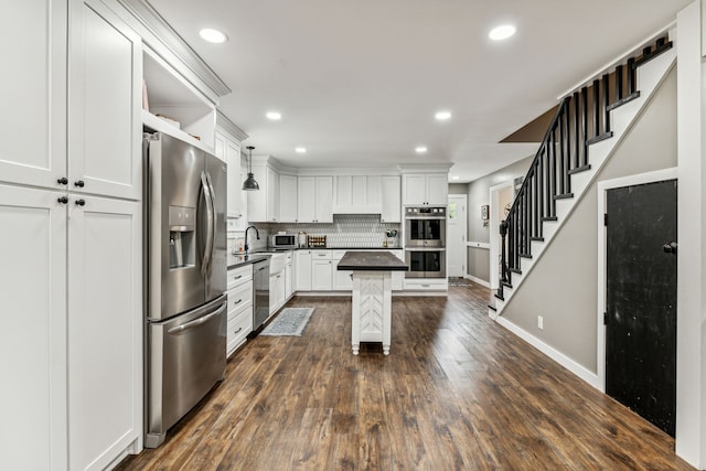 kitchen featuring a center island, dark hardwood / wood-style floors, stainless steel appliances, decorative backsplash, and decorative light fixtures