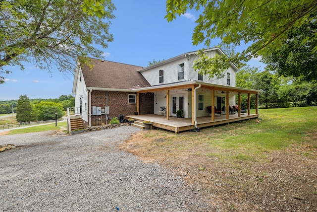 back of property with a wooden deck and a yard