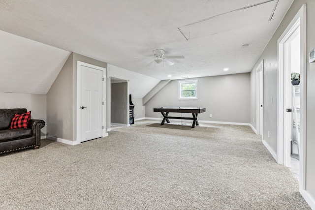 rec room featuring ceiling fan, vaulted ceiling, carpet floors, and a textured ceiling