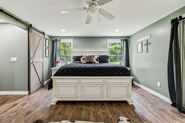 bedroom featuring a barn door, hardwood / wood-style flooring, and ceiling fan