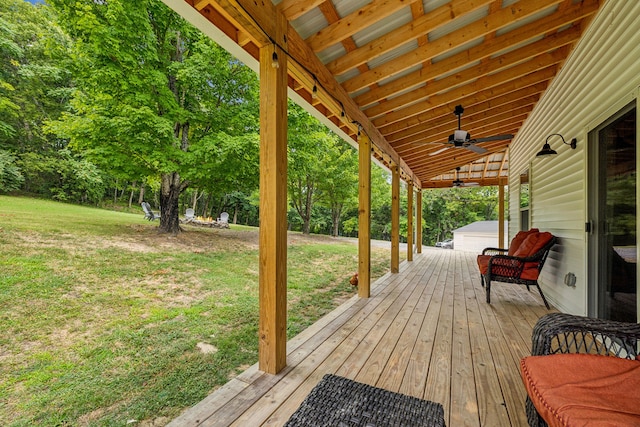 wooden terrace featuring ceiling fan and a lawn