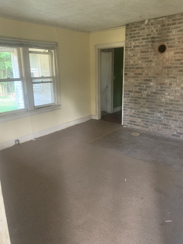 empty room featuring brick wall and a textured ceiling