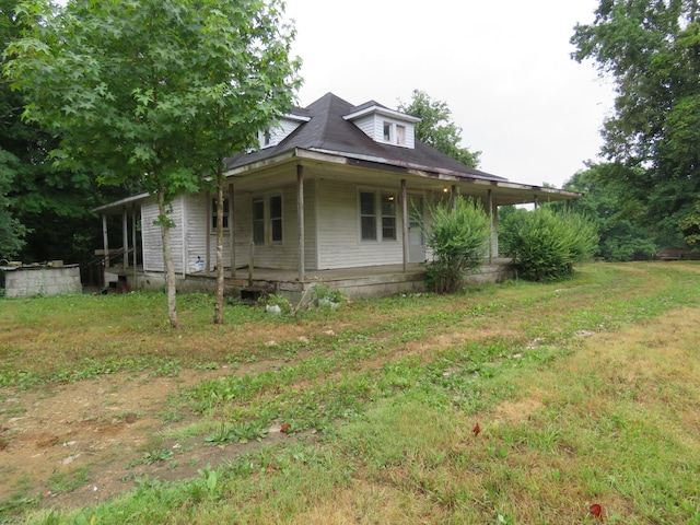 view of side of home with covered porch and a lawn