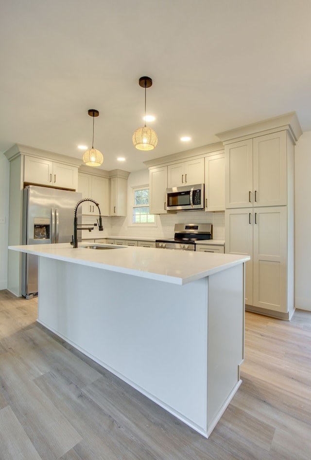 kitchen featuring a kitchen island, sink, light hardwood / wood-style floors, appliances with stainless steel finishes, and decorative light fixtures