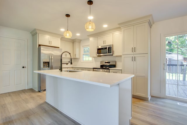 kitchen featuring stainless steel appliances, hanging light fixtures, a center island with sink, and a healthy amount of sunlight