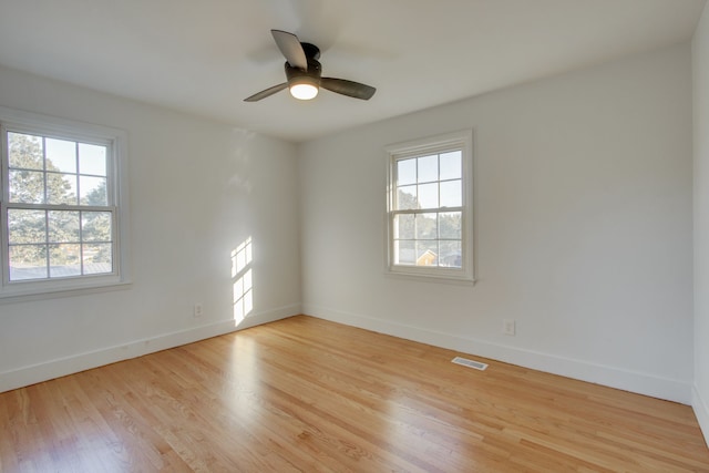 spare room featuring ceiling fan, light hardwood / wood-style flooring, and a healthy amount of sunlight