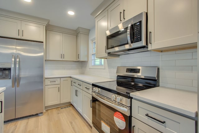 kitchen featuring stainless steel appliances, light hardwood / wood-style floors, and tasteful backsplash