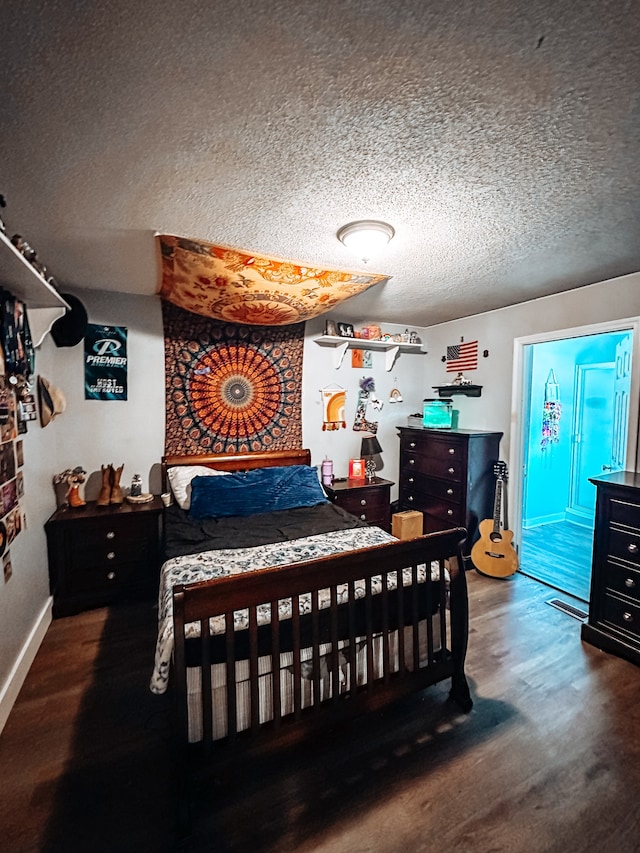 bedroom with dark hardwood / wood-style floors and a textured ceiling