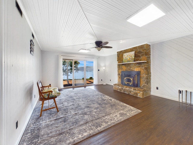 living room featuring a fireplace, a water view, hardwood / wood-style floors, and ceiling fan