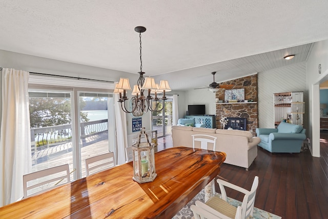 dining room featuring a fireplace, dark hardwood / wood-style floors, vaulted ceiling, and a textured ceiling