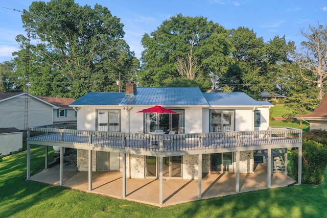 rear view of house featuring a deck, a patio, and a lawn