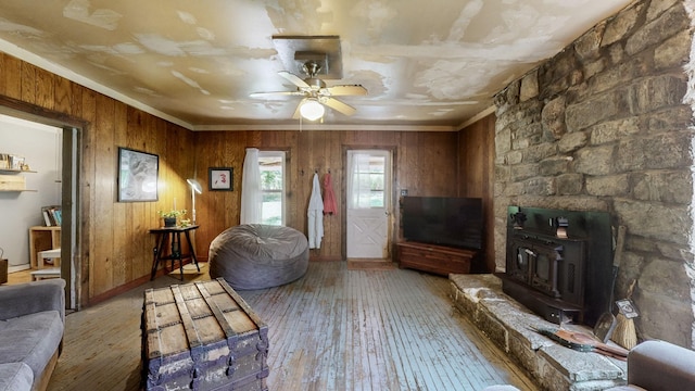 living room with hardwood / wood-style flooring, ceiling fan, wood walls, and ornamental molding