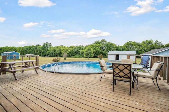 view of swimming pool featuring a wooden deck and a storage shed