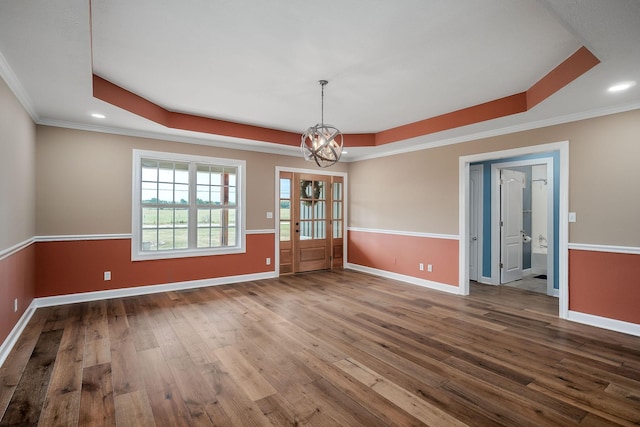 unfurnished dining area with hardwood / wood-style flooring, an inviting chandelier, ornamental molding, and a raised ceiling