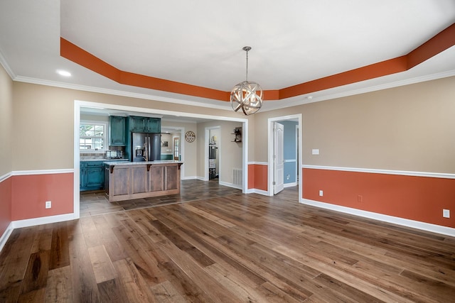 interior space with dark hardwood / wood-style floors, a raised ceiling, ornamental molding, and a chandelier