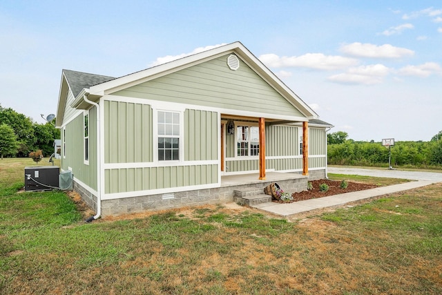 view of front facade with covered porch, cooling unit, and a front lawn